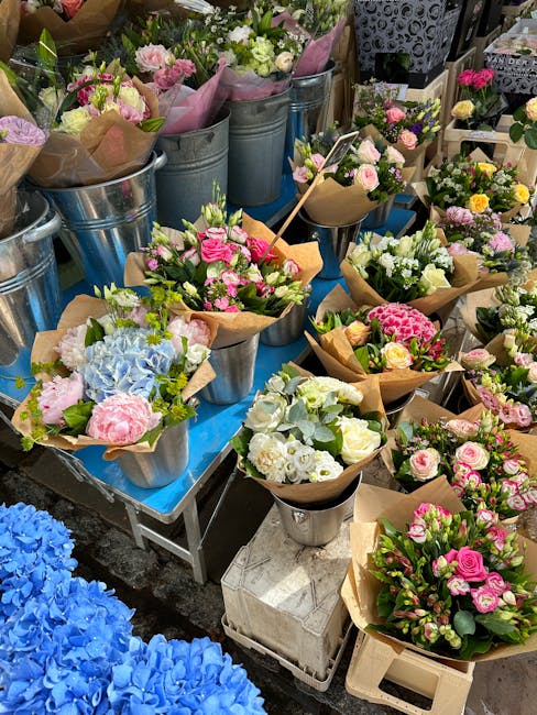 A vibrant display of freshly arranged flower bouquets at a local florist shop, featuring a variety of pastel and bright colors including pink, white, blue, and yellow blooms. The bouquets are wrapped 