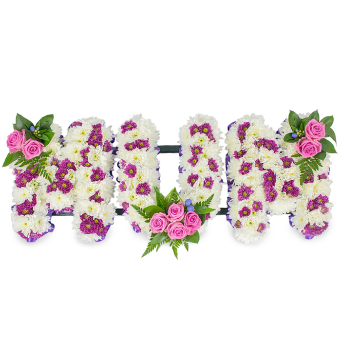 Presented against a plain white backdrop, this personalised funeral tribute spells MUM in three-dimensional, capital letters formed from a dense base of pristine white chrysanthemum blooms. The chrysanthemums create a plush, tactile surface - soft, layered, and uniform - while clusters of vibrant purple-magenta spray chrysanthemums are artfully dispersed to give each letter subtle pockets of colour and depth. A delicate purple ribbon outlines the edges of the letters, its narrow sheen defining contours and lending a quiet, considered finish to the shape. Three distinctive posies of pink spray roses punctuate the layout: a small cluster of two to three roses with fern and dark green foliage at the top left of the first M, a larger bouquet of four to five vivid pink roses nestled into the lower curve of the U with abundant greenery and tiny blue accent blossoms, and a mirrored cluster on the top right of the second M. The rich greens - including fern fronds - add sculptural movement and a cooling contrast to the warm pinks; the minute blue flowers offer delicate highlights that catch the eye. Thin, unobtrusive dark bars connect the letters horizontally, providing structural integrity so the tribute sits evenly on a stand or table for a wake or service. The overall mood is respectfully traditional yet personalised: tactile, fragrant with rose and chrysanthemum, and finished with careful ribbonwork that speaks to experienced floristry often requested for memorials in Maidenhead and surrounding villages such as Bray and Cookham.