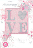 This image shows a softly romantic anniversary card that seems perfectly at home in a quiet Maidenhead living room, its colours and details capturing the feeling of an English spring. The focal point is the word LOVE, written in large, gently raised letters that shimmer with fine blush-pink glitter, edged in cool silver. The letter O is transformed into a sparkling heart, filled with denser silver texture that looks almost like tiny crystals, adding a touch of drama within the overall softness. Behind the lettering, a wash of pastel pink forms a gentle backdrop, similar to the early blossoms in nearby Braywick Park. Around this centrepiece, a ring of delicate flowers unfolds in blush, mauve, and ivory tones, their petals painted with an almost watercolour lightness. Fine lines suggest stems and swirling vines, leading the eye around the design as though following the curve of a carefully arranged bouquet. Small flourishes-scattered petals, looping swirls, and a few slender butterflies picked out in silver-grey-create an impression of movement, like a breeze passing through a garden. Above and below the central motif, the words On Our Anniversary and I love you today and always are written in an understated, elegant script that harmonises with the curving floral lines. The card's overall look is tender and intimate, quietly luxurious yet deeply heartfelt, much like a hand-tied anniversary arrangement delivered across Maidenhead by Flower Delivery Maidenhead to mark years of shared memories and gentle, enduring romance.